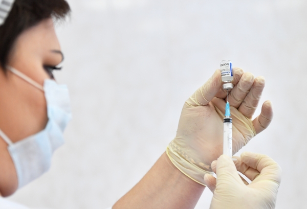 Медицинская сестра набирает в шприц вакцину 