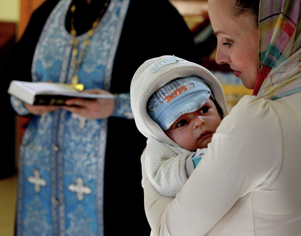 Женщина с ребенком во время обряда крещения младенца в храме Святителя Николая Чудотворца во Владивостоке