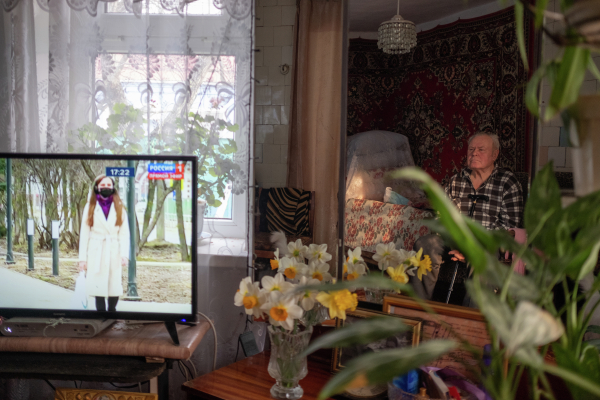 Пожилой мужчина смотрит телевизор у себя дома во время самоизоляции в связи с эпидемией коронавируса в Краснодарском крае